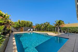 a swimming pool with blue water in a backyard at Sea Spray- Private Pool, Beach, Table Tennis in The Entrance