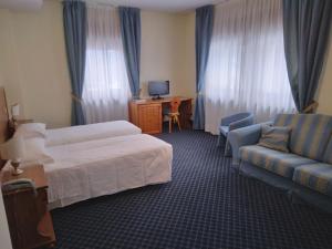 ein Hotelzimmer mit einem Bett und einem Sofa in der Unterkunft Hotel Belvedere Dolomiti in Pieve di Cadore