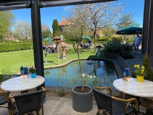 a patio with two tables and a pond at Appartementen De Zegelskoël in Heijenrath