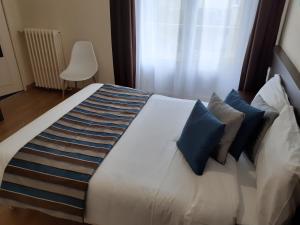 a bedroom with a large white bed with blue pillows at Le Chapeau Rouge in Alençon