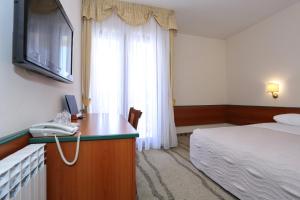 a hotel room with a bed and a desk with a phone at Hotel Mediteran in Zadar