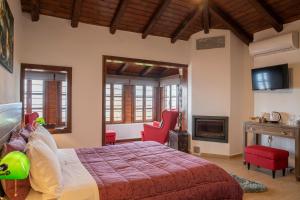 a bedroom with a bed with red chairs and a fireplace at Guesthouse Ourania in Palaios Panteleimonas