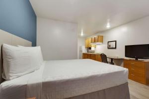 una camera da letto con un letto bianco e una televisione di WoodSpring Suites Conroe a Conroe