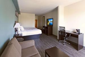 a hotel room with a bed and a desk and a couch at Sleep Inn & Suites in Foley