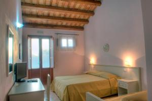 a bedroom with a bed and a desk with a television at Baglio Antico in Fulgatore