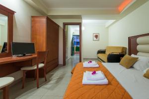 a hotel room with a bed and a desk with towels at Caretta Beach Resort & WaterPark in Kalamaki