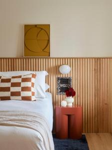 a bedroom with a bed and a red table with a lamp at The Isla in Batemans Bay