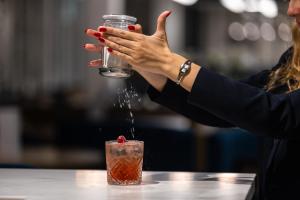a woman is sprinkling water on a drink at Hotel Indigo Cagnes-sur-Mer by IHG in Cagnes-sur-Mer +291 photos