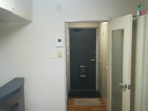 einen Flur mit einer Tür, die zu einem Flur mit einer schwarzen Tür führt in der Unterkunft Yakuendai Wacore Elegance in Chiba