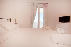 a white bedroom with a large white bed and a window at Villa BiancaRosa with amazing views! in Mikonos