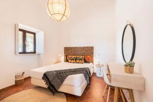 a white bedroom with a bed and a mirror at Quinta da Baleeira in Tavira