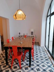 埃武拉的住宿－Casa da Freiria，一间带木桌和红色椅子的用餐室