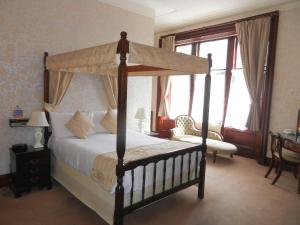 a bedroom with a canopy bed and a chair at Morangie Hotel Tain in Tain
