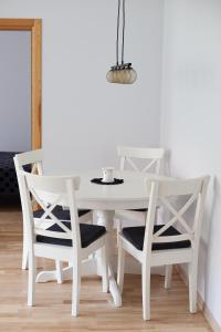 a white dining room table with two chairs and a white wall at Prie Pušyno in Birštonas