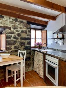 a kitchen with a table and a stone wall at La Nozaleda in Infiesto