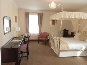 a bedroom with a canopy bed with a desk and a chair at Morangie Hotel Tain in Tain