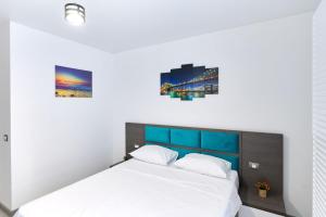 une chambre avec un lit blanc avec deux tableaux au mur dans l'établissement Turquoise Apartment Nord10 - Pool n Parking, à Mamaia 31 autres photos