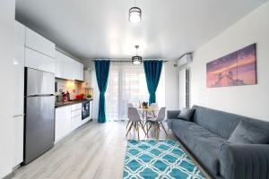 un salon avec un canapé et une cuisine dans l'établissement Turquoise Apartment Nord10 - Pool n Parking, à Mamaia
