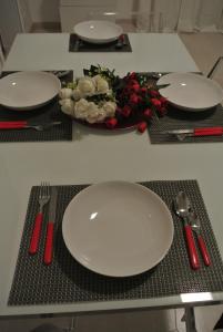 una mesa con dos platos blancos y un tazón de flores en Boncompagni Suite Roma, en Roma