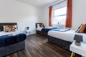 pokój z 2 łóżkami i kanapą w obiekcie M18 Abbey Hey Guesthouse w Manchesterze