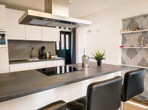 eine Küche mit weißen Schränken und einer Theke mit Stühlen in der Unterkunft Studio with sauna in Amsterdam