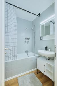 y baño blanco con lavabo, bañera y ducha. en Topeingerichtete große 2-Zimmer Wohnung, en Immenstaad am Bodensee