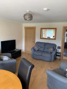 a living room with a couch and a tv at No 52 - Apartment with Lounge and Dining Area - No kitchen in Ullapool