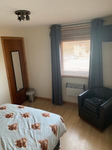 um quarto com uma cama, uma cadeira e um espelho em No 52 - Apartment with Lounge and Dining Area - No kitchen em Ullapool