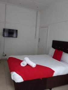 łóżko z dwoma ręcznikami na czerwonym kocu w obiekcie Linze lodge w mieście Durban
