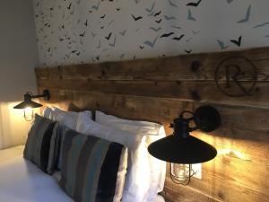 a bedroom with a wooden headboard with birds on the wall at The Randolph Hotel in Southwold
