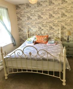 1 dormitorio con cama blanca y papel pintado con motivos florales en The Glen Mona Hotel en Maughold