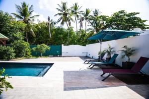 a pool with chairs and an umbrella next to a fence at Magnifique villa avec piscine in Sainte-Anne