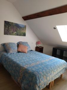 Schlafzimmer mit einem Bett mit blauer Decke in der Unterkunft Le logis aux digitales in La Croix-aux-Mines