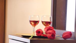 two glasses of wine on a table with red flowers at House Chrysoula Mitsokopi in Sarti