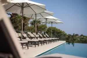 een rij stoelen en parasols naast een zwembad bij Aparthotel Joel in Novalja