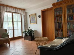 ein Wohnzimmer mit einem Sofa, Stühlen und Bücherregalen in der Unterkunft Koschak Wirt & Weinbauer in Heimschuh