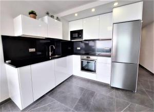 a kitchen with white cabinets and a refrigerator at Apto El Faro Puerto Deportivo in Marbella +9 photos