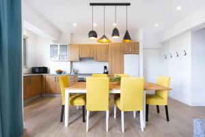 a kitchen and dining room with a wooden table and yellow chairs at Home2Book Urban Chic Sebastian in Santa Cruz de Tenerife