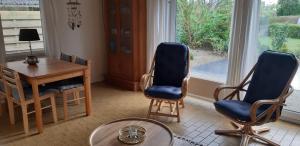 een woonkamer met 2 stoelen, een tafel en een raam bij Robbenoort 45 in Lauwersoog
