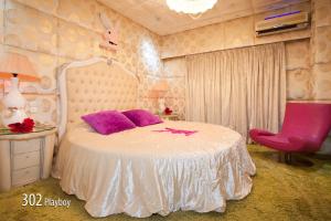 a bedroom with a white bed and a pink chair at Hotel Priamos-&Alpha;dults Only in Athens
