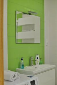 zieloną łazienkę z umywalką i lustrem. w obiekcie Capital Towers - Apartament Pop-art z widokiem na rzekę w mieście Rzeszów