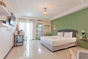 1 dormitorio con cama y pared verde en Cozzi by Grand Airport Resort, en Lat Krabang