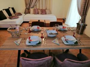 a wooden table with plates and wine glasses on it at Malvazios Villas Azure Sea Villa in Gythio