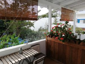 un porche con un banco de madera y flores en Apanemia 2, en Kini