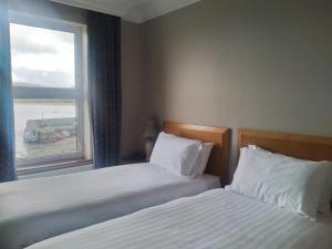 2 camas en una habitación de hotel con ventana en The Beach Hotel, en Mullaghmore