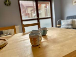 two cups sitting on top of a wooden table at Apartament Przytulny w Krynicy-Zdrój in Krynica Zdrój