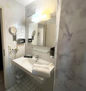 Baño blanco con lavabo y espejo en Hotel Freihof, en Stuttgart