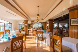 a restaurant with white tables and chairs and windows at Playa Grande Resort in Cabo San Lucas
