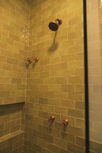 a shower with a yellow tiled wall and bronze fixtures at Øko Villa in Juquei