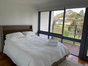 a bedroom with a large bed and a balcony at The Beachcomber in Sanctuary Point